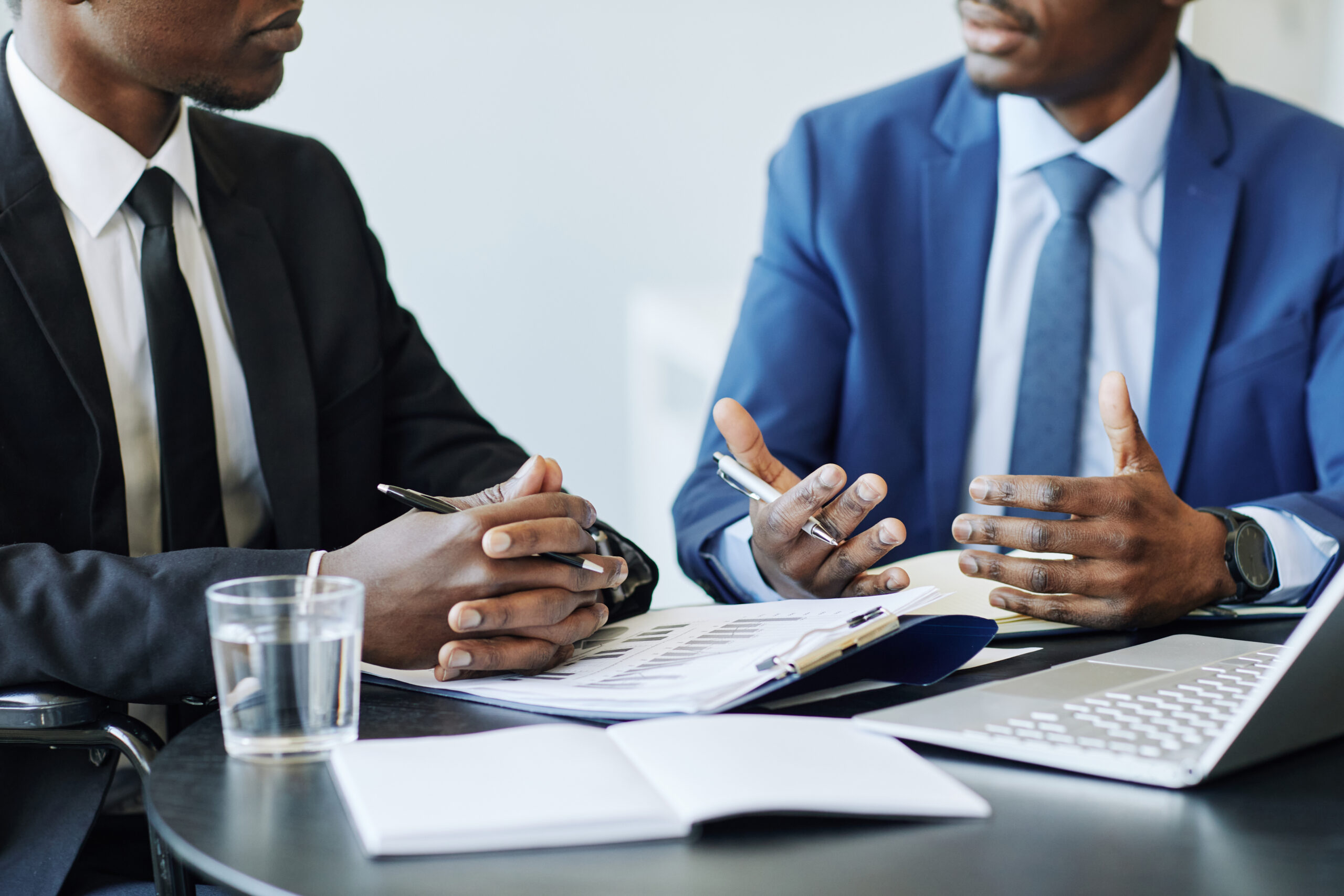 Cropped shot of two successful business partners discussing deal at meeting table in office